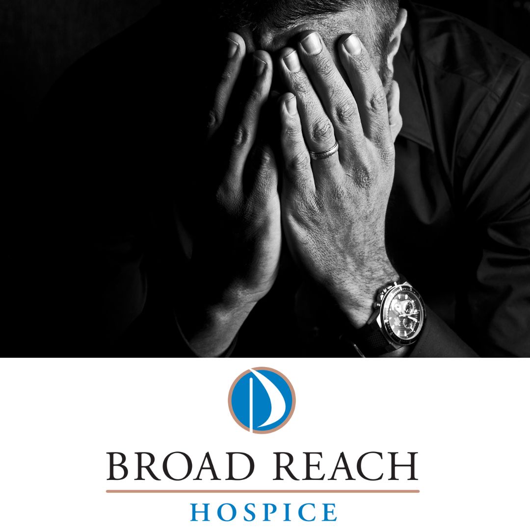 A man sits with his face in his hands above the Broad Reach Hospice logo.